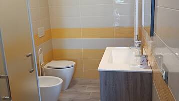 Un baño con inodoro, lavamanos y zona de ducha.