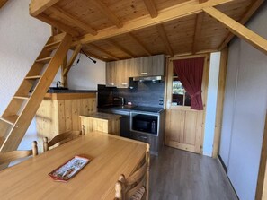 Ein Holzinnenraum mit Küche, Esstisch und einer Treppe.