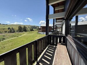 Ein Balkon mit Blick auf ein grünes Feld und entfernte Gebäude.