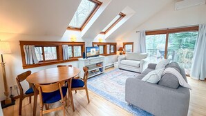 Een moderne woonkamer met een eethoek, een bank, een televisie en een open haard.