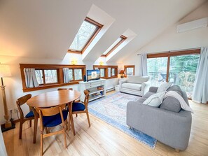 Ein modernes Wohnzimmer mit Essbereich, einer Couch, einem Fernseher und einem Kamin.