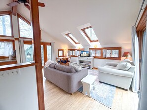 Un loft espacioso con techos altos, tragaluces, comedor y un rincón de estar acogedor.