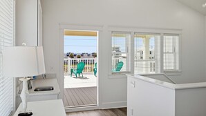 Habitación con vista a una terraza, un lavamanos, una silla y un ventanal.