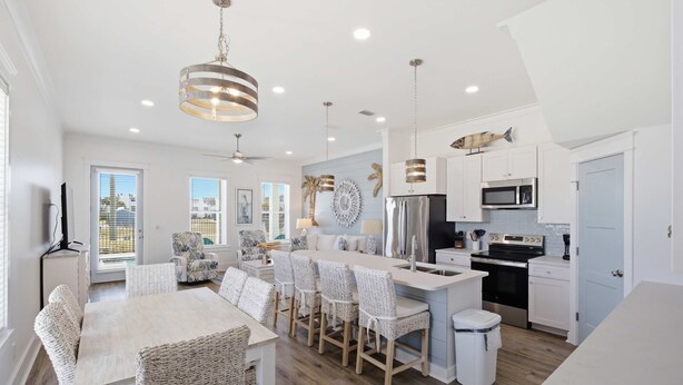Una cocina moderna con una isla central, muebles blancos y electrodomésticos de acero inoxidable.