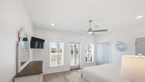 Un dormitorio con cama, cómoda, espejo, ventilador de techo y ventana con persianas.