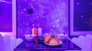 A table with a plate of croissants, two glasses, and two bottles of water, set against a starry wall. - L'Etage des nuages - Jacuzzi & precious moments (La Flèche)