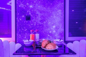 Una mesa con un plato de cruasanes, dos vasos y dos botellas de agua, frente a una pared decorada con estrellas.