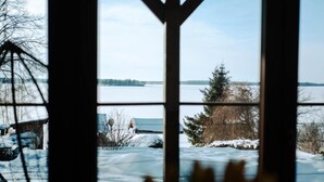 A view through a window with a snow-covered landscape, a body of water, and a distant shoreline. - Fuleda Apartments Mazury.Holiday (Fuleda)