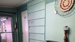 Una habitación con una bandeja de madera que sostiene un florero con rosas blancas, un adorno de ganchillo en la pared y una chimenea con un florero decorativo.