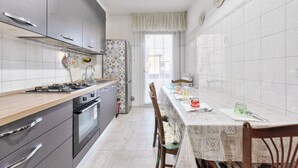 A kitchen with a dining table, chairs, cabinets, and a window. - Home OF Mestre (Venezia)