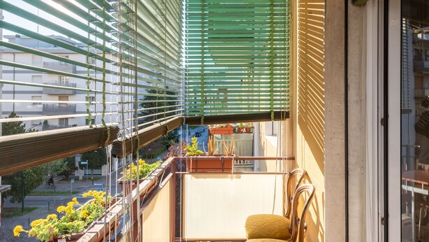 A balcony with a chair, potted plants, and a view of the street. - Home OF Mestre (Venezia)