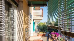 A narrow balcony with a sliding glass door, a small table, and potted plants. - Home OF Mestre (Venezia)