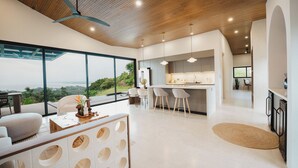 A modern interior with a kitchen, dining area, and seating with a view. - Modern adults-only villa with private plunge pool and panoramic ocean-to-mountain views. (Manuel Antonio)
