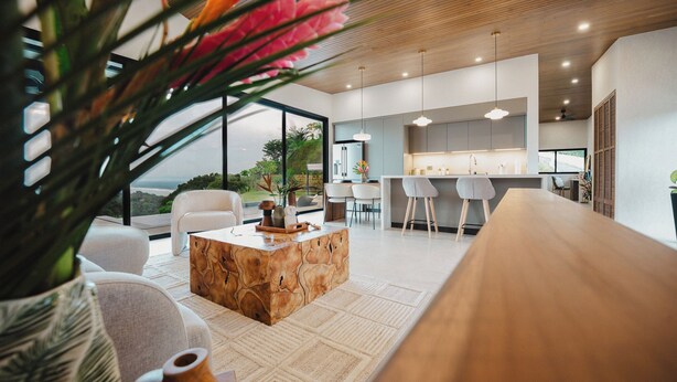 A modern kitchen with a central island, bar stools, and a large window overlooking a garden. - Modern adults-only villa with private plunge pool and panoramic ocean-to-mountain views. (Manuel Antonio)