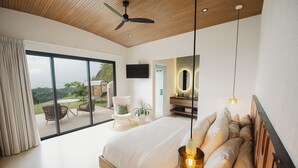 A modern bedroom with a large bed, a ceiling fan, a TV, and a view of the outdoors. - Modern adults-only villa with private plunge pool and panoramic ocean-to-mountain views. (Manuel Antonio)