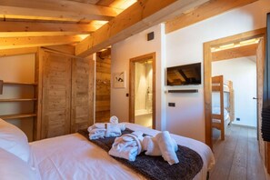 A wooden cabin-style bedroom with a bed, towels, a TV, and a wooden door. - 2nd floor, hammam, balcony, fireplace or stove, parking, 190m², Les Gets (Les Gets)