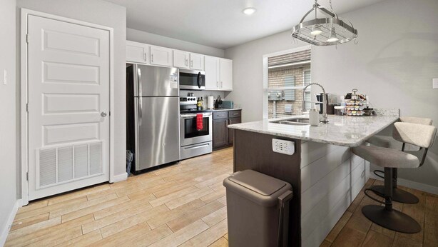 A modern kitchen with stainless steel appliances, a large island with bar stools, and a window with blinds. - Cozy Stay_2Bedrooms_Work Space_Near Attractions (Fort Smith)