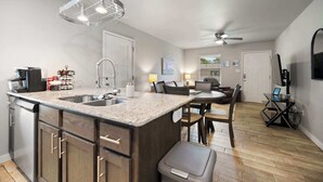 A modern kitchen with granite countertops, stainless steel appliances, and a dining area with a round table and chairs. - Cozy Stay_2Bedrooms_Work Space_Near Attractions (Fort Smith)