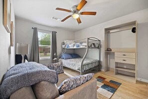Ein Schlafzimmer mit Etagenbett, Deckenventilator, Schreibtisch und einem Fenster mit Vorhängen.