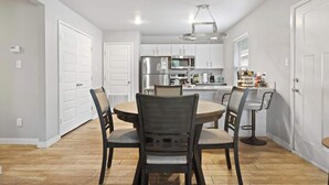 A modern kitchen with white cabinets, stainless steel appliances, and a dining area with a round table and chairs. - Cozy Stay_2Bedrooms_Work Space_Near Attractions (Fort Smith)