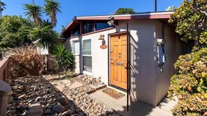 Une maison avec une porte en bois, un petit porche et un chemin de pierre menant à l’entrée.