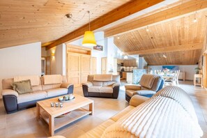 A spacious living area with a high ceiling, wooden beams, and a dining area with a view. - 4th floor, balcony, parking, ski locker, 132m², Le Grand Bornand (Le Grand-Bornand)