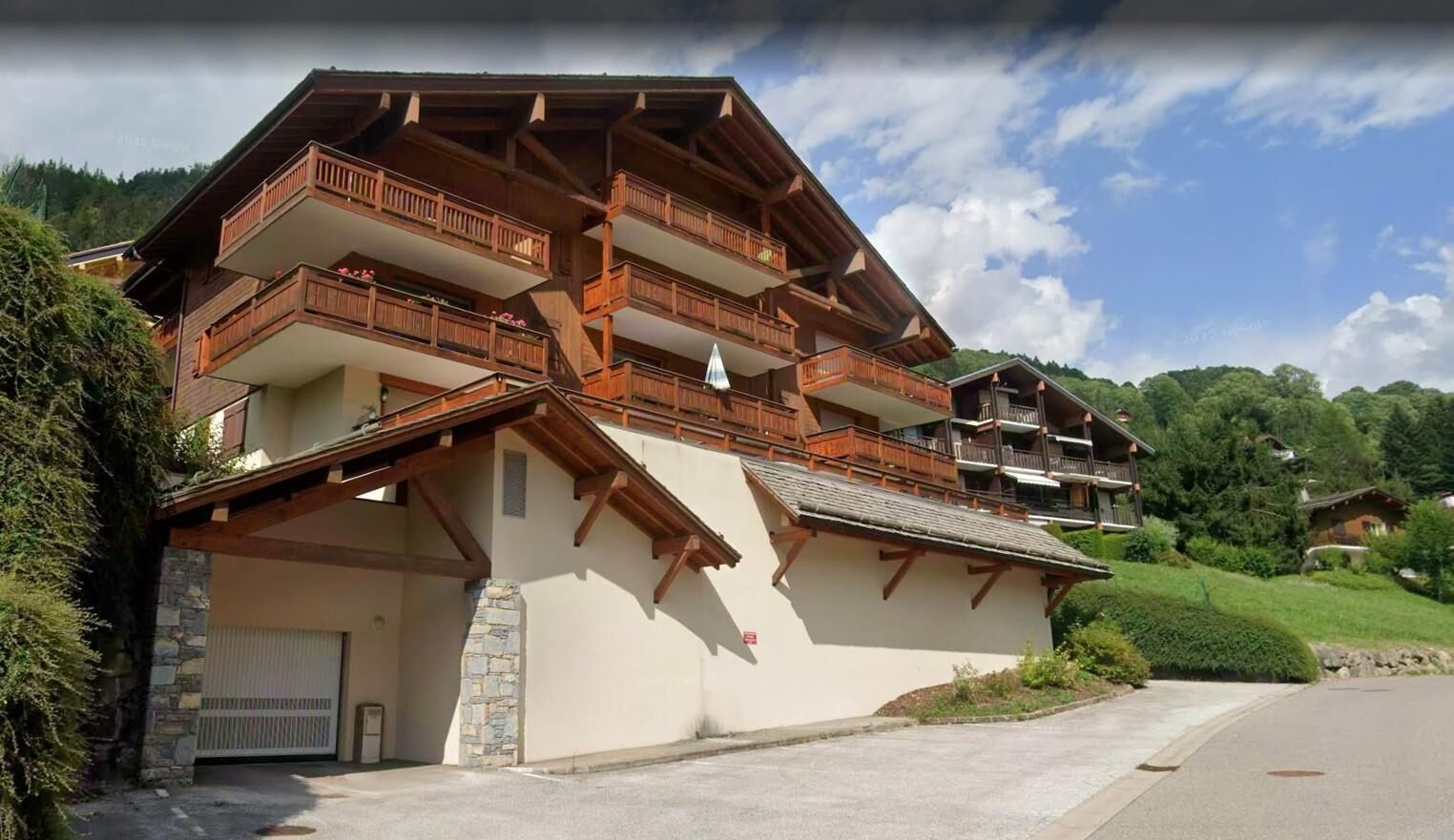 Un chalet à plusieurs étages doté de balcons, d’un garage et d’une allée.