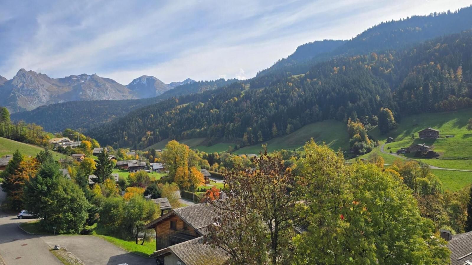 Un village rural avec des maisons, une route et des montagnes en arrière-plan.