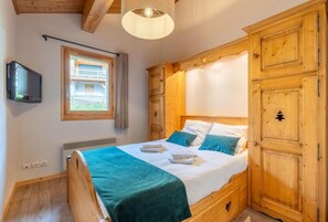 A bedroom with a bed, wooden wardrobe, a television, and a window. - 4th floor, balcony, parking, ski locker, 132m², Le Grand Bornand (Le Grand-Bornand)
