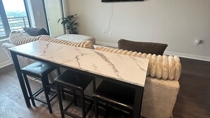 Una sala de estar moderna con comedor, ventilador de techo, televisor de pantalla plana y un ventanal grande.