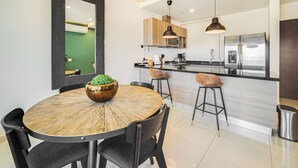 A modern kitchen with a central island, bar stools, and a large refrigerator. - Zona Romantica Condo | Rooftop Pool | 1 Min Beach (Puerto Vallarta)