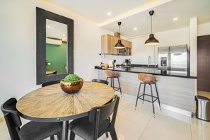 A modern kitchen with a central island, bar stools, and a large refrigerator. - Zona Romantica Condo | Rooftop Pool | 1 Min Beach (Puerto Vallarta)