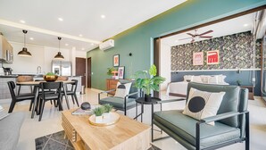 A modern living room with a sofa, coffee table, and dining area. - Zona Romantica Condo | Rooftop Pool | 1 Min Beach (Puerto Vallarta)