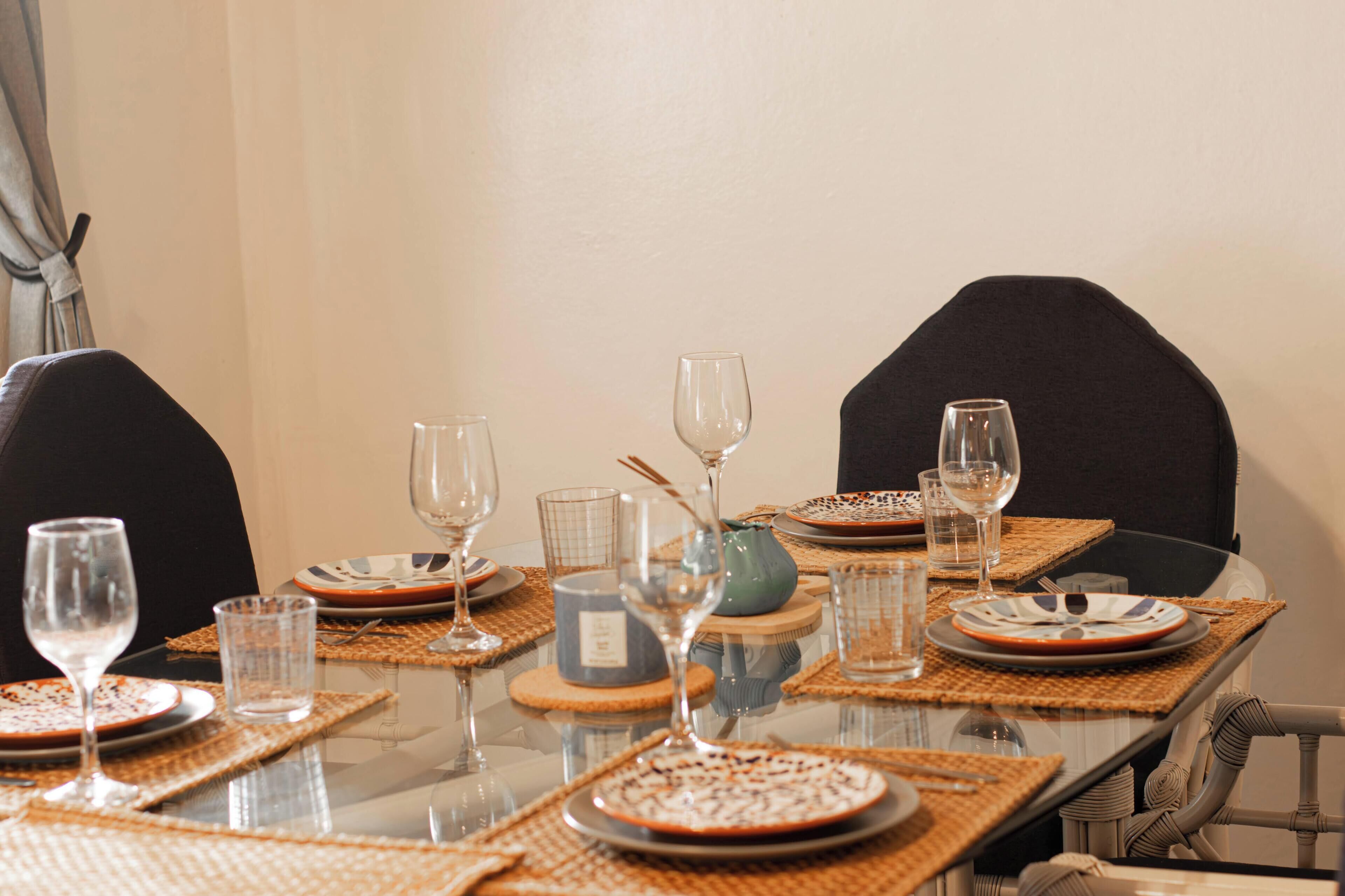 A dining table set with plates, glasses, and a vase.