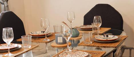 A dining table set with plates, glasses, and a vase.