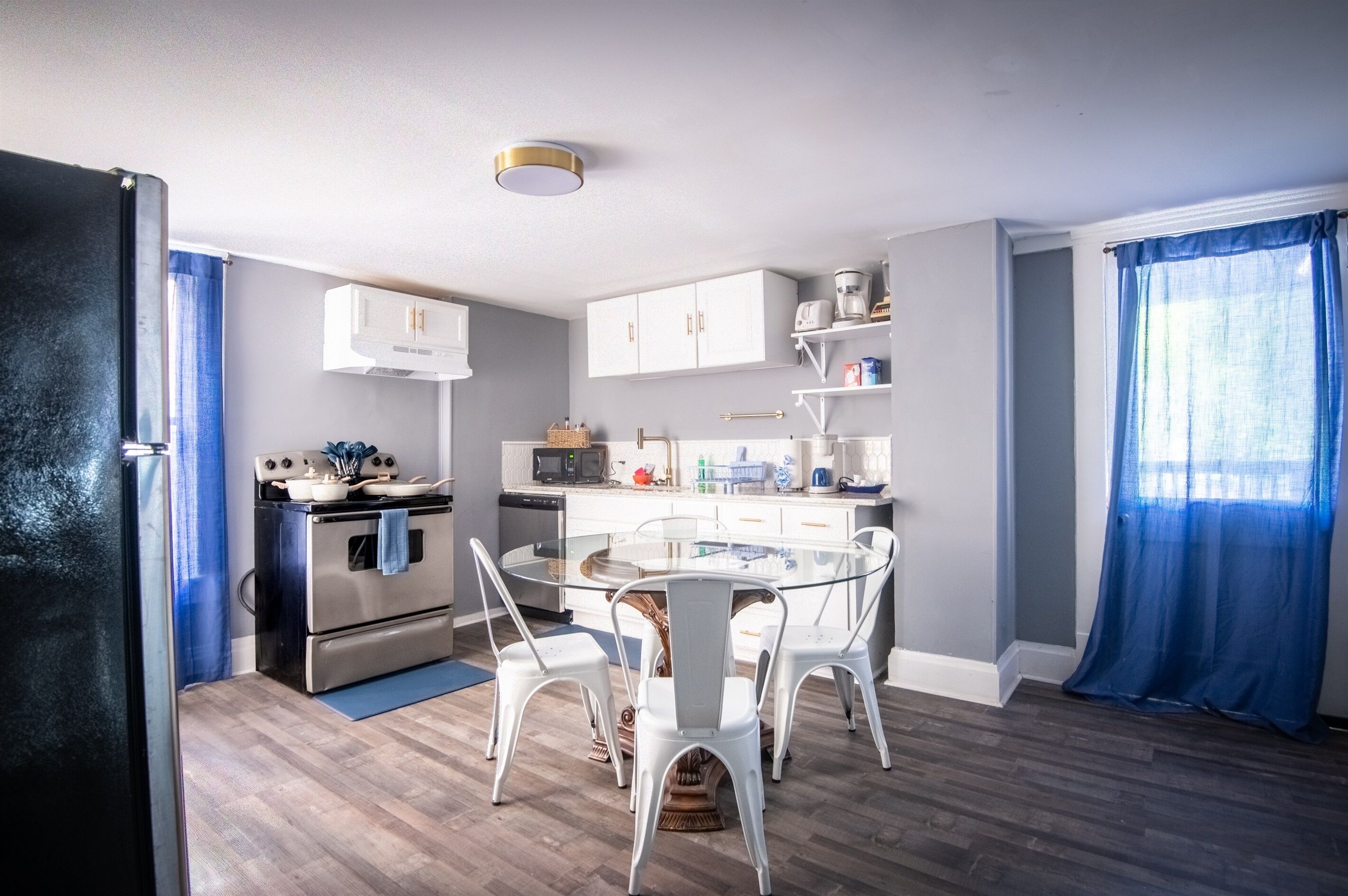 A modern kitchen with white cabinets, a round glass table, and white chairs.