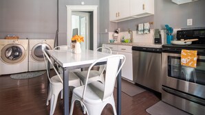 Una cucina moderna con elettrodomestici in acciaio inossidabile, un tavolo da pranzo con sedie e una lavatrice nell'angolo.