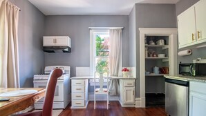 Une cuisine de taille réduite, avec des meubles blancs, une cuisinière, un four à micro-ondes et un lave-vaisselle.