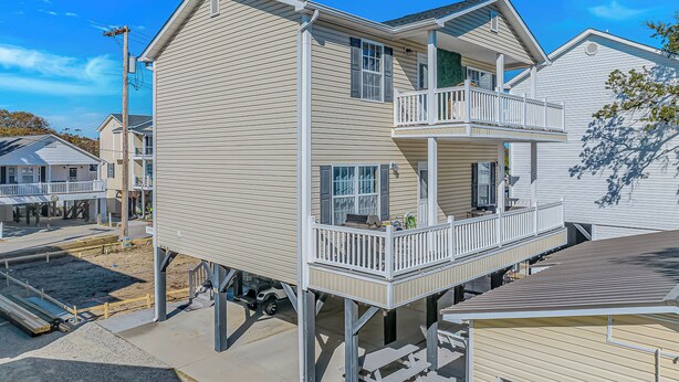 A multi-story building with a balcony on the second floor, a covered patio area, and a dock extending into the water. - Sleeps 16-inside OL w/ Limo Golf Cart &Game Room (Myrtle Beach)