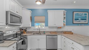 A kitchen with white cabinets, a stainless steel refrigerator, a dishwasher, and a window with blinds. - Sleeps 16-inside OL w/ Limo Golf Cart &Game Room (Myrtle Beach)
