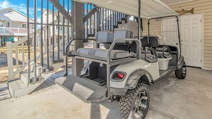 A covered golf cart with seating, a step-up platform, and a garage door in the background. - Sleeps 16-inside OL w/ Limo Golf Cart &Game Room (Myrtle Beach)