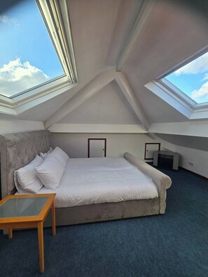 A bedroom with a large bed, a small table, and two skylights. - Sleeps 6 - St Helens - 50 Mins to Peak District (St Helens)