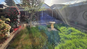 Un jardin où l’on trouve une grande variété de plantes et un abreuvoir pour les oiseaux.