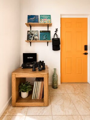 Una habitación con una mesa de madera, una estantería con libros, una cámara y una puerta.