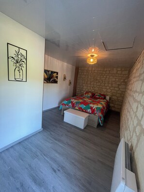Ein Schlafzimmer mit einem Bett, einem Nachttisch, einer Wandleuchte und einem dekorativen Wandbild.