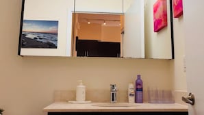 A bathroom with a large mirror, a sink with toiletries, and a view of the beach.