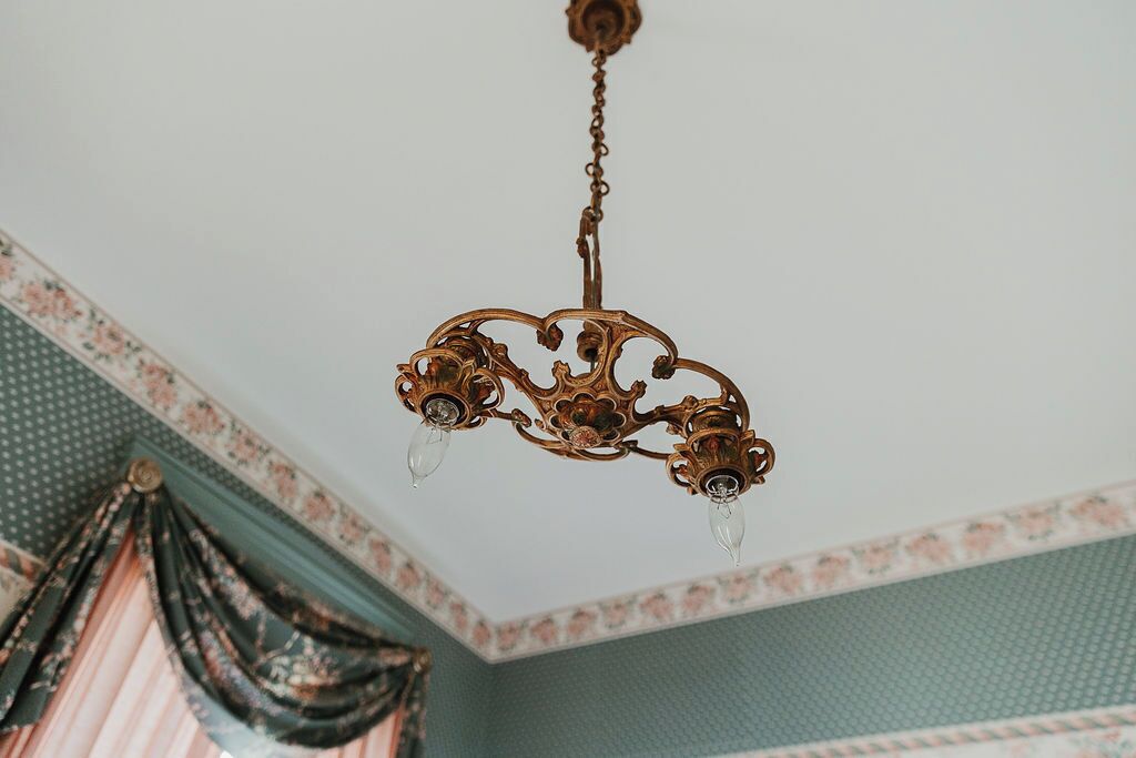 A chandelier with ornate metalwork and three light bulbs.