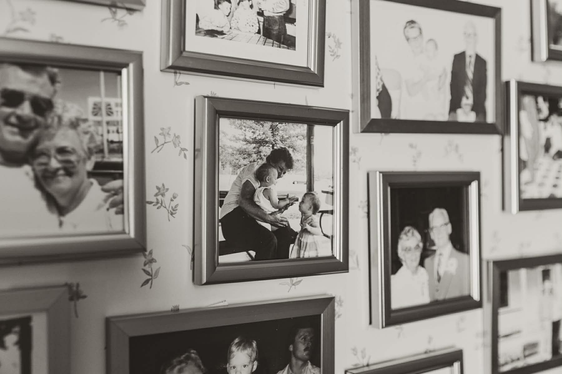 En væg med flere indrammede fotografier, hvoraf nogle viser mennesker og andre viser natur.