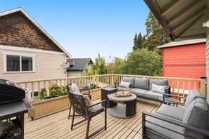 Eine Terrasse mit Gartenmöbeln, einem Grill und einem roten Gebäude im Hintergrund.