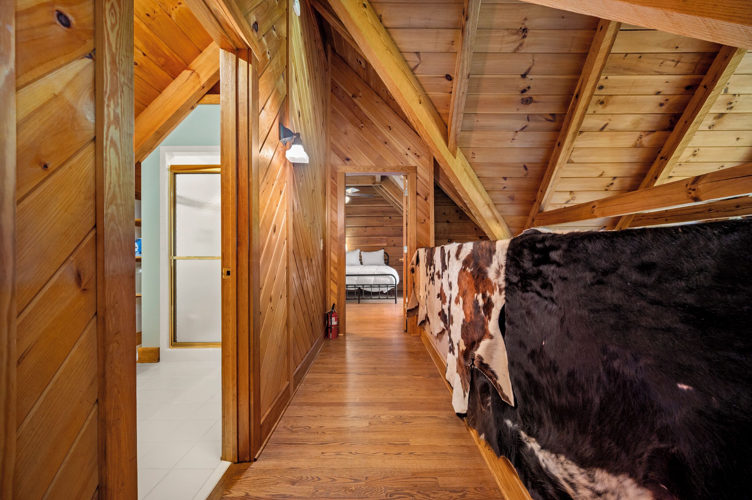 A wooden hallway with a bed and a large animal hide wall.